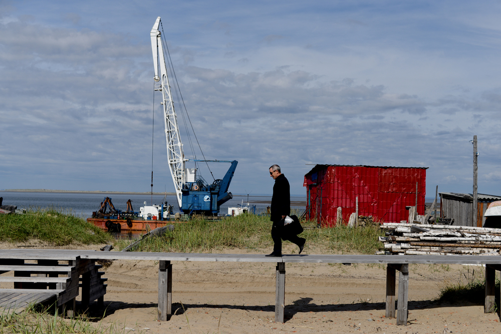 Глава администрации идет на работу. На главной улице поселка сделаны деревянные мостки, чтобы ходиь не по песку. 